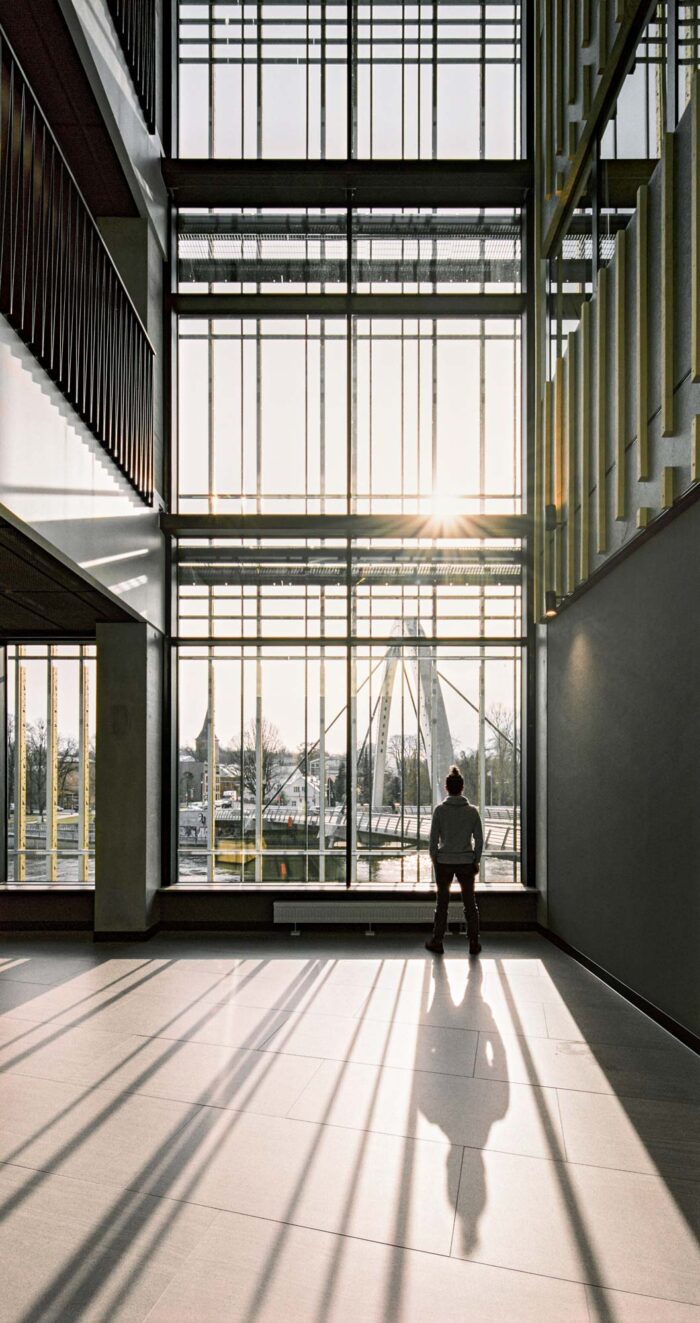 Vertical glass window with man standing and long shadows