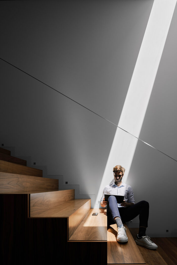 Man sitting in staircase reading magazine with light beam