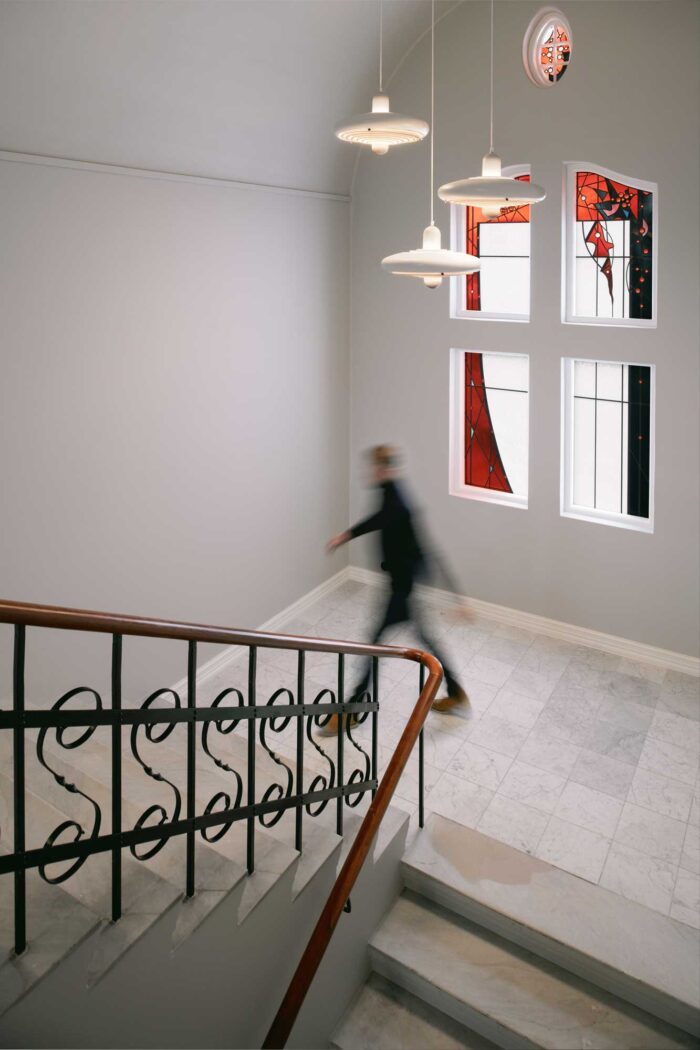 Staircase with wooden rail and a man walking up in a hurry