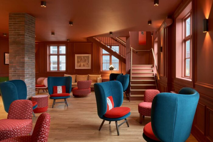 Lounge room with red walls and blue chairs spread across