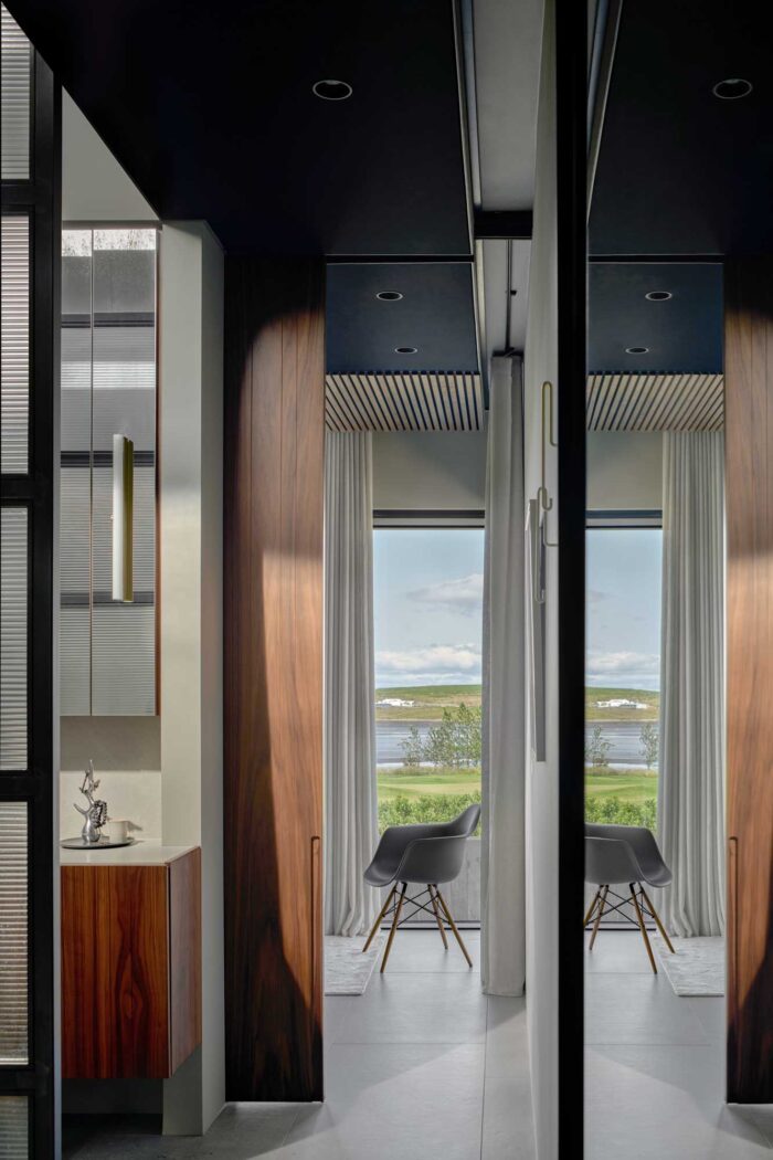 Corridor view of the bathroom with a minimal design chair in the background