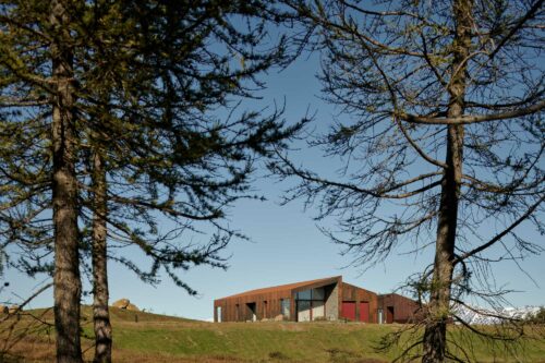 House made of corten steel with large trees around