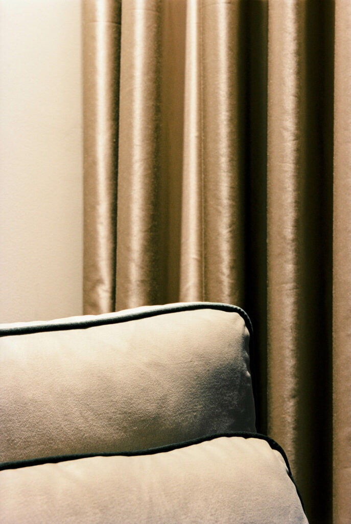 Fabric detail of a pillow with soft materials grey color and golden curtain in the background