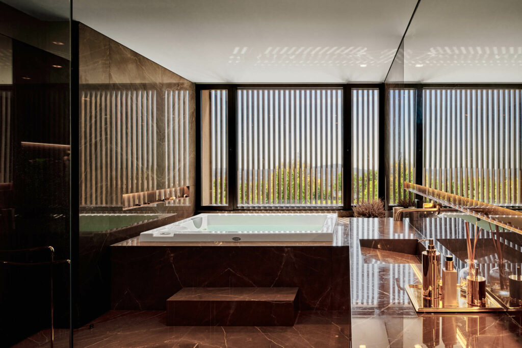 Luxurious bathroom with rose marble and jacuzzi with large window facing the exterior