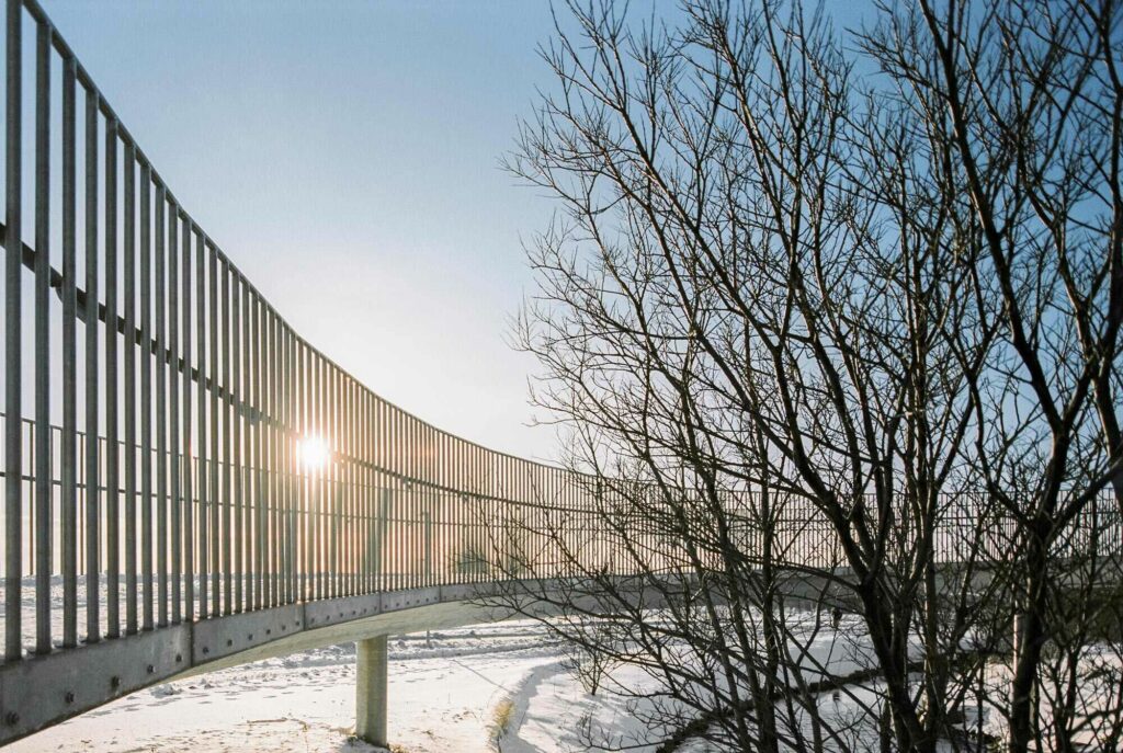 Concrete bridge with metalic hand rail and trees during snowy winter