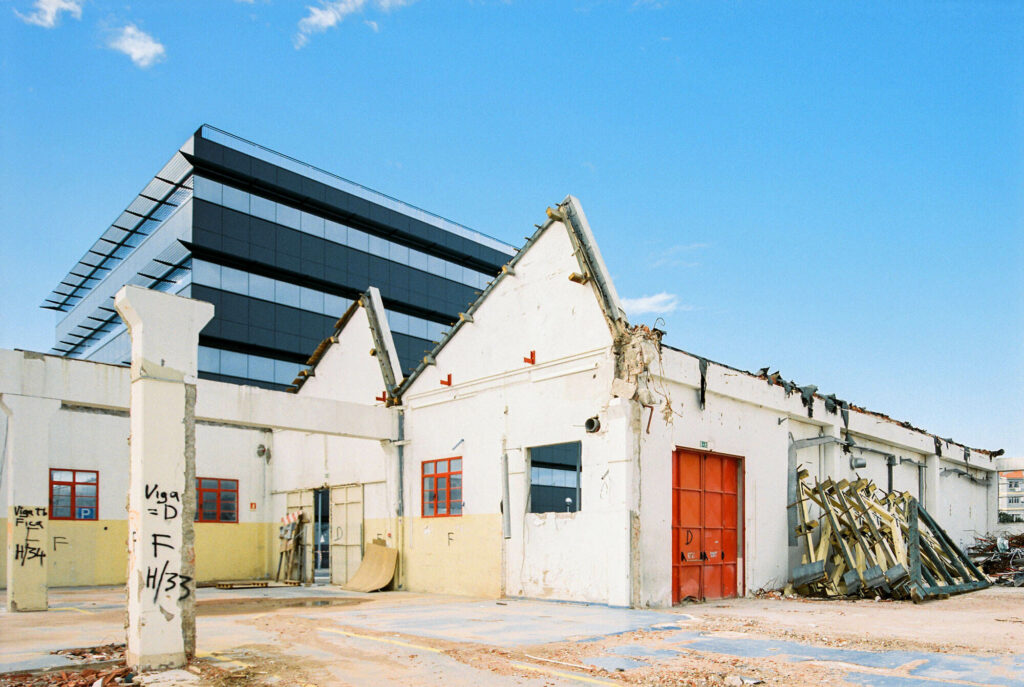 Building demolished with tilted roof and modern building in the background