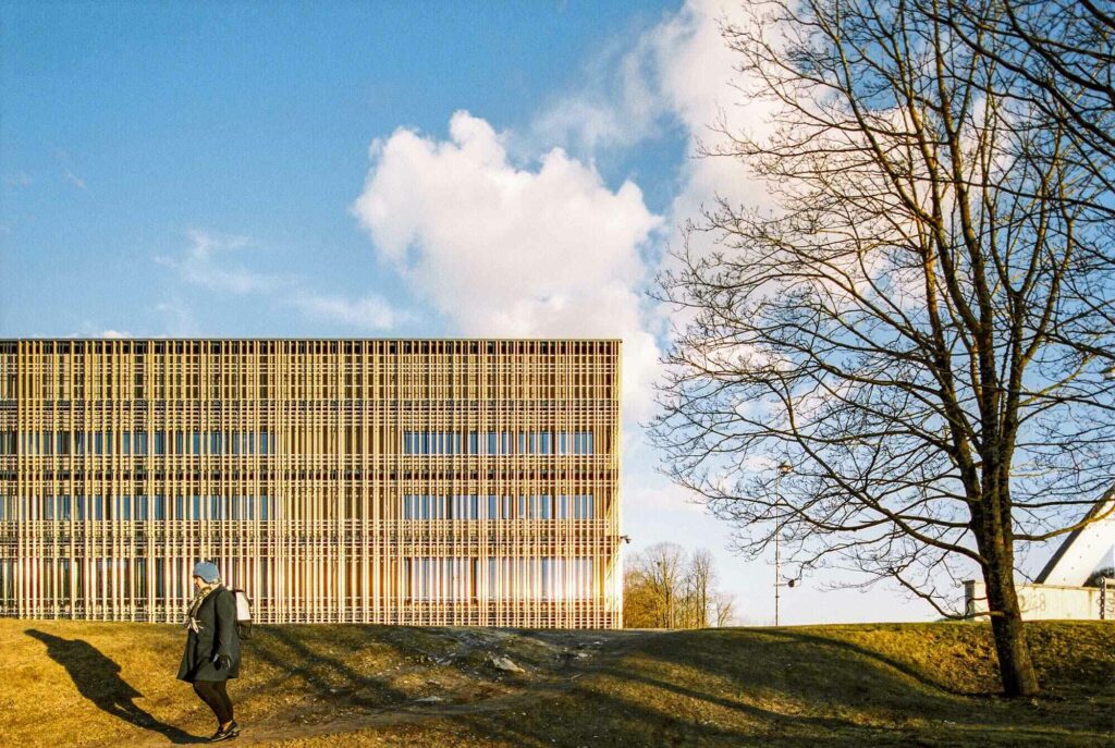 Golden cladding building in Tartu, Estonia with woman walking by