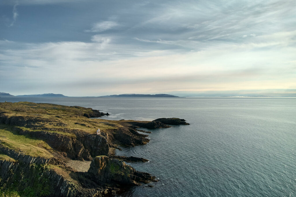 Fjords in Iceland with small wooden cabin at the edge of the cliff overlooking the ocean