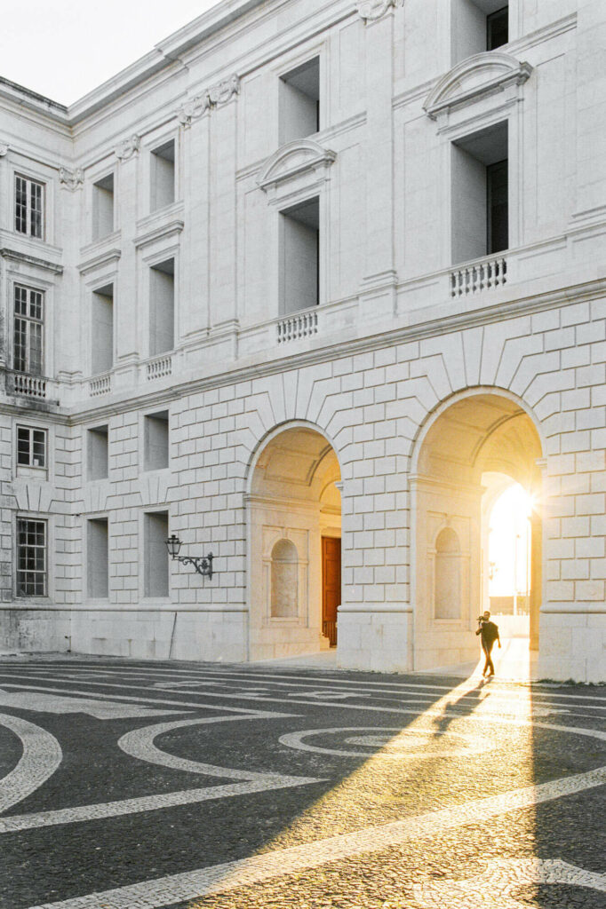 Classical architecture building with arches and man walking with sun in the background and long shadows