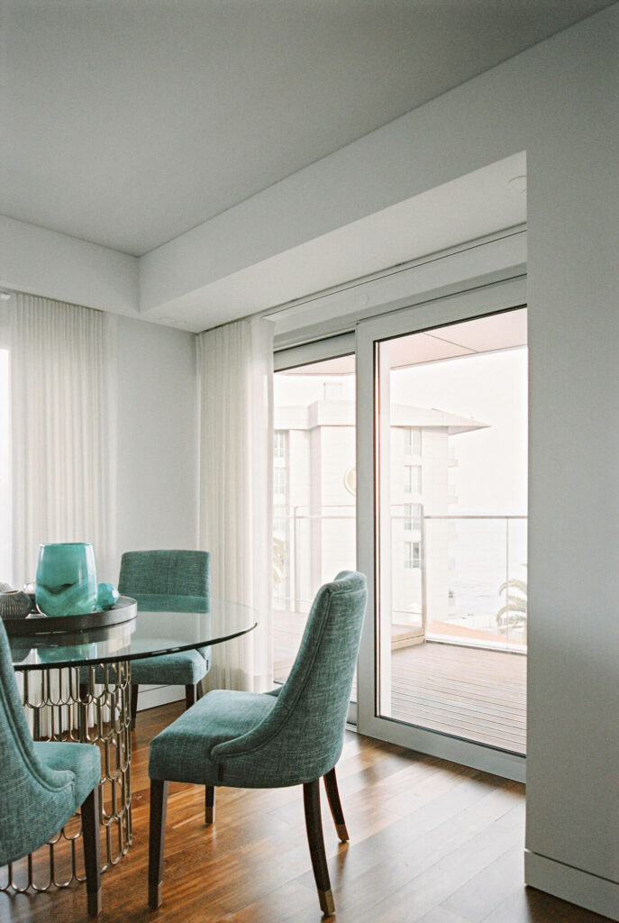 Living room with green chairs and large windows facing the street